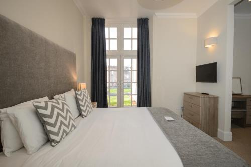 Un dormitorio con una cama blanca y un televisor. en Ardconnel Court Apartments, en Inverness