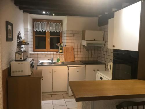 a small kitchen with white cabinets and a sink at Fontaine Gargot - La sapinière 5p in Poligny