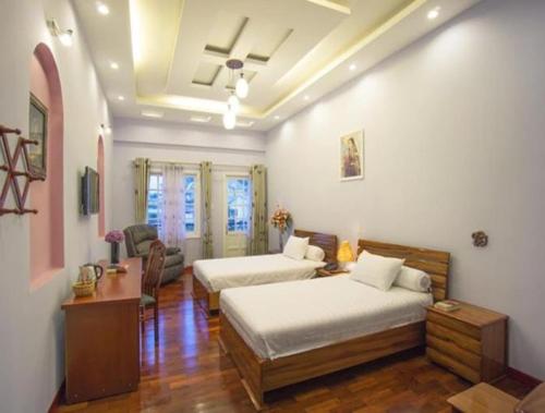 a bedroom with two beds and a table and a couch at Dalat Terrasse Des Roses Villa in Da Lat