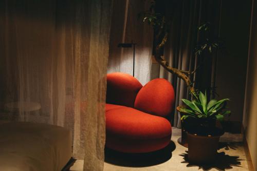 a red chair sitting next to a potted plant at Hotel K5 in Tokyo