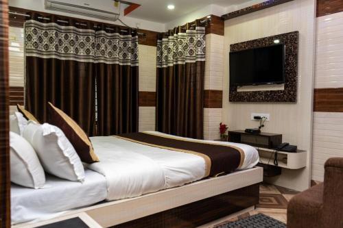 a bedroom with a bed and a flat screen tv at Tirupati Lodge NJP in Siliguri