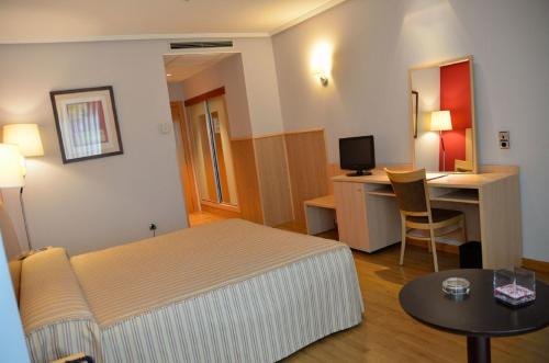 um quarto com uma cama, uma secretária e uma mesa em Hotel Villa de Benavente em Benavente