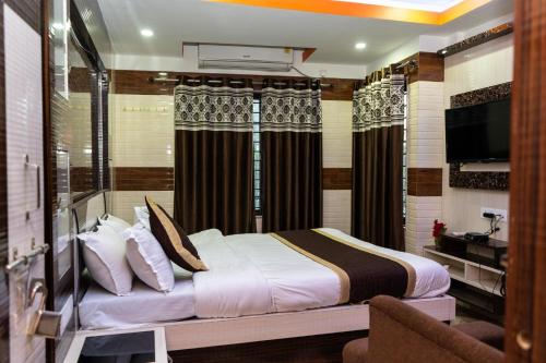 a bedroom with a bed and a television in a room at Tirupati Lodge NJP in Siliguri