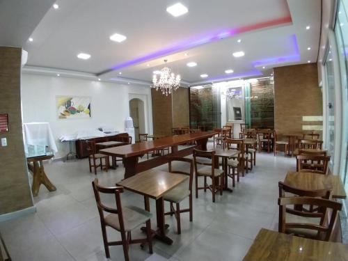 un ristorante con tavoli e sedie in legno e luci viola di Casablanca Palace Hotel a Frutal