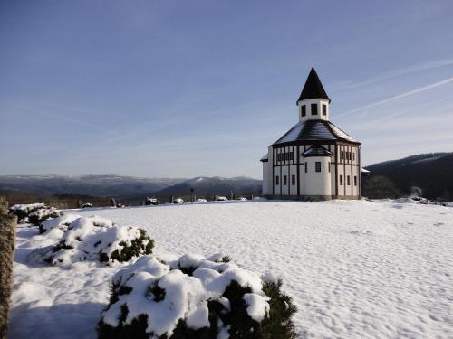 a church on top of a snow covered hill at Penzion Zrzka in Kořenov