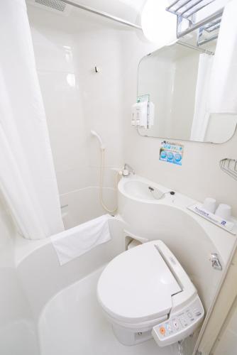 a white bathroom with a toilet and a mirror at Super Hotel Shinyokohama in Yokohama
