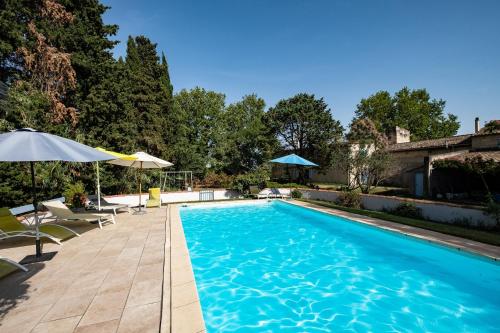 une piscine avec chaises et parasols dans une cour dans l'établissement Gîte de La Treille Mas Médaille, à Arles