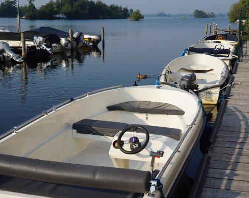 a row of boats docked at a dock in the water at VISSERSLUST Rooms, Apartments and Houseboats in Vinkeveen