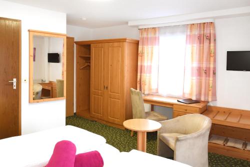 a hotel room with a bed and a desk and a window at Pension Freiheit in Pfronten
