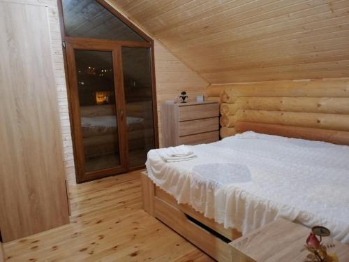 een slaapkamer met een bed in een houten hut bij Cottage house Niniela in Batoemi