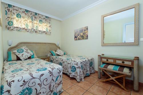 a bedroom with two beds and a mirror and a table at VIP Apartamentos Nogal- Adults Only in Playa del Ingles