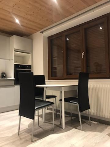 a kitchen with a white table and black chairs at Studio Brides les bains in Brides-les-Bains