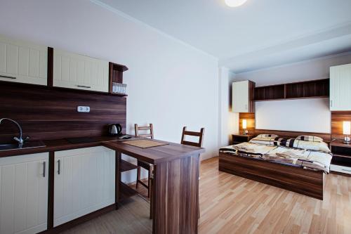 a kitchen with a table and a bed in the background at Kocsis Apartman és Camping in Mosonmagyaróvár