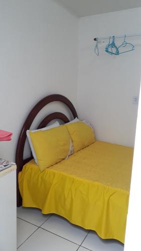 a bed with yellow sheets and a wooden headboard at Suíte zona Sul de ilhéus próximo a praia in Ilhéus