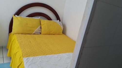 a bed with yellow and white pillows in a room at Suíte zona Sul de ilhéus próximo a praia in Ilhéus