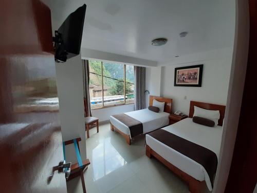 a hotel room with two beds and a window at Flower's House MachuPicchu in Machu Picchu