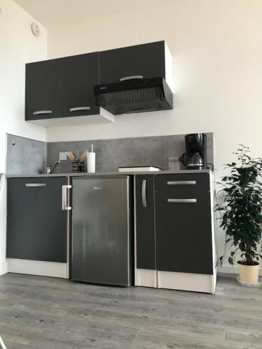 uma cozinha com um frigorífico preto e um fogão em Studio Meublé Vue Mer em Le Havre