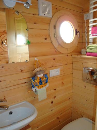 La salle de bains est pourvue de murs en bois, de toilettes et d'un lavabo. dans l'établissement Maison d'hôtes La Roulotte des 4 Saisons, à Sazeray