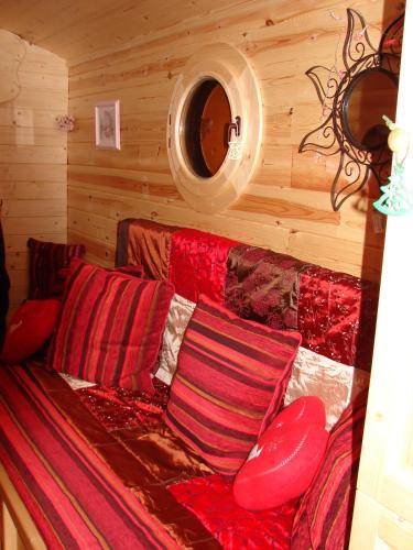 - un canapé rouge avec des oreillers dans une chambre en bois dans l'établissement Maison d'hôtes La Roulotte des 4 Saisons, à Sazeray