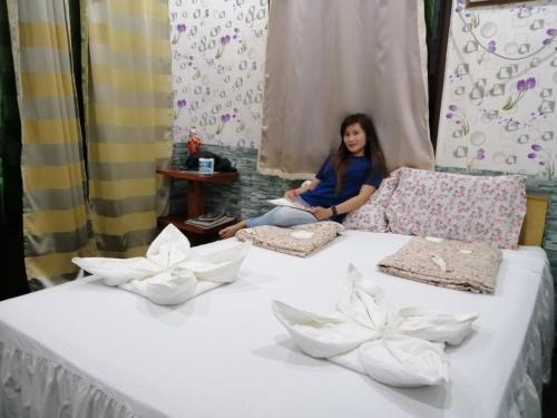 a woman sitting on a bed with flowers on it at Villa Encantador Resort in San Vicente