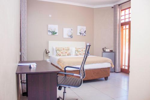 een slaapkamer met een bed en een bureau met een stoel bij Angel Boutique Hotel in Maputo