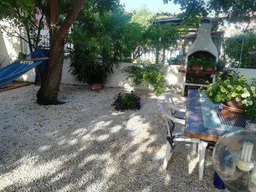un jardín con mesa, sillas y un árbol en B&B I Mari, en Torpè