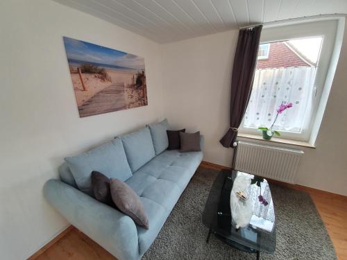 a living room with a blue couch and a window at FeWo-Butze 3 Deichblick Strandnähe ca. 750m in Dornumersiel