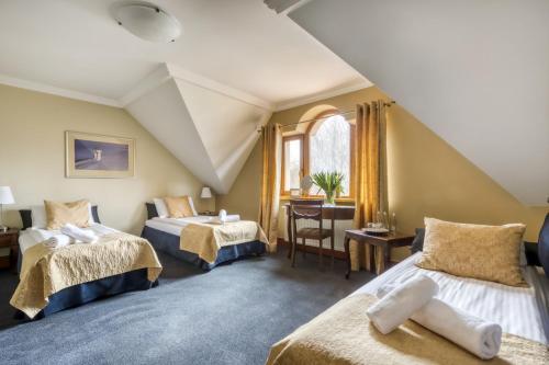 - une chambre mansardée avec 2 lits et une table dans l'établissement American House Baletowa, à Varsovie