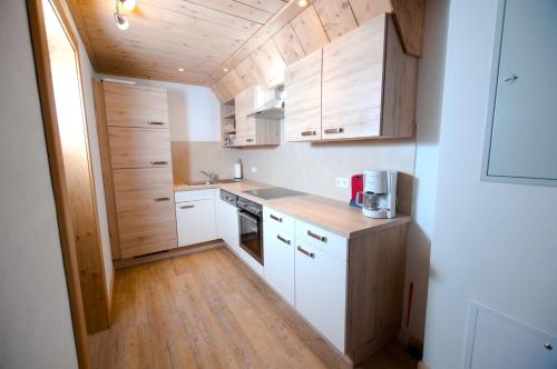 a small kitchen with white cabinets and wooden floors at Appartements Wallner in Uttendorf