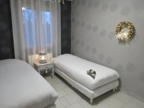 um quarto com duas camas e uma coroa de flores na parede em Chambre d'hôtes La Clé du Bonheur em Manthelon