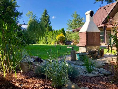 a garden with a stone fireplace in front of a house at Willa Brzozówka in Milówka
