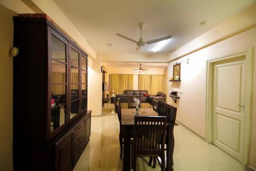 a dining room with a table and chairs and a living room at Misty Rosa Luxury Serviced Apartments in Kottayam