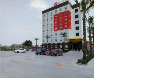 a large building with cars parked in a parking lot at Hotel Hi ! Torreon Aeropuerto-Galerías in Torreón
