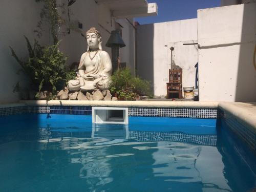 a buddha statue sitting next to a swimming pool at Hotel Ibiza in Villa Gesell