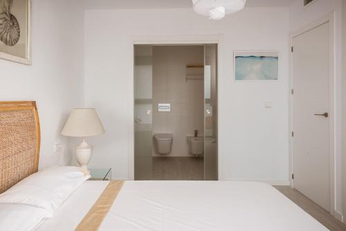 een witte slaapkamer met een bed en een badkamer bij Modern sea front Sunny Beach in Alicante