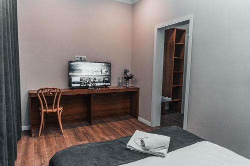 1 dormitorio con escritorio, TV y silla en ЖОМАРТ, en Aktobe