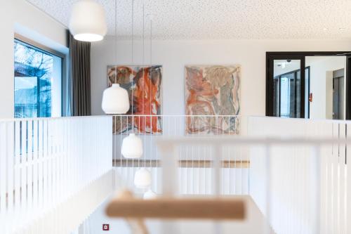 a white staircase with two lights and paintings on the wall at Mari Pop Hotel in Ried im Zillertal