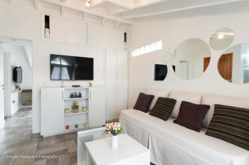 una sala de estar blanca con un sofá blanco y espejos en M&T Centrico en San Martín de los Andes