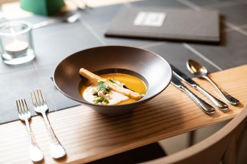 a bowl of soup sitting on a table with silverware at Mari Pop Hotel in Ried im Zillertal
