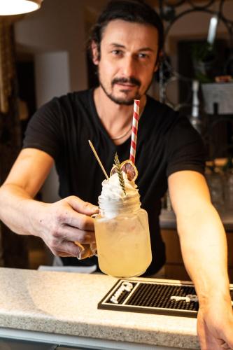 a man sitting at a counter holding a drink at Mari Pop Hotel in Ried im Zillertal