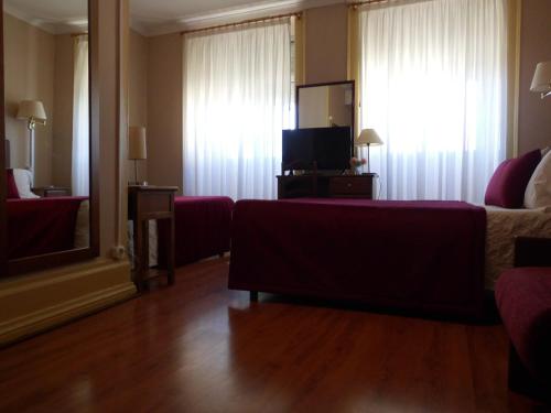 uma sala de estar com um sofá e uma televisão num quarto em Hotel Larbelo em Coimbra