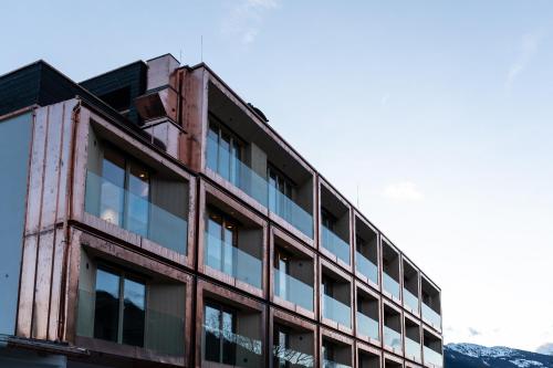 an old building with glass windows and mountains in the background at Mari Pop Hotel in Ried im Zillertal