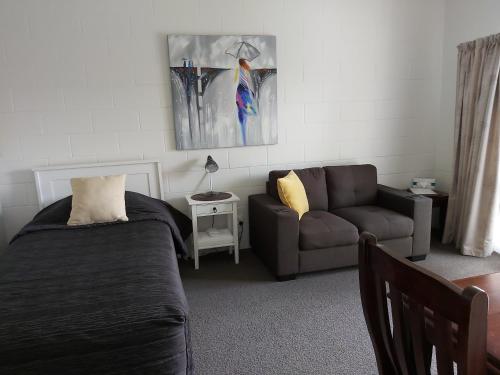 a bedroom with a bed and a couch and a chair at Matador Motel in Carterton