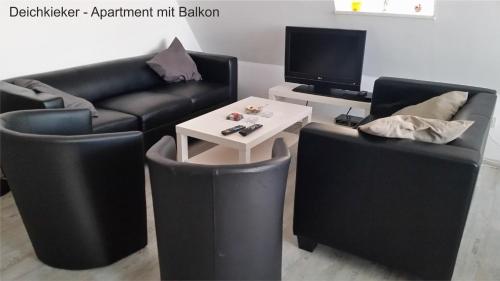 ノルトダイヒにあるHaus Ostfrieslandのリビングルーム(黒い革張りの椅子2脚、テーブル付)