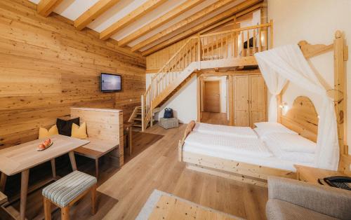 ein Schlafzimmer in einem Blockhaus mit einem Bett und einer Treppe in der Unterkunft Biohotel Rupertus in Leogang