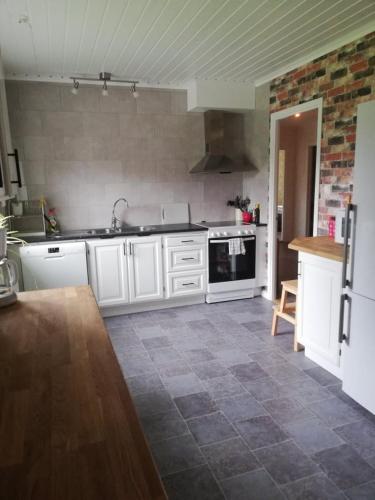 a kitchen with white cabinets and a tile floor at Gästhuset 32 in Vansbro