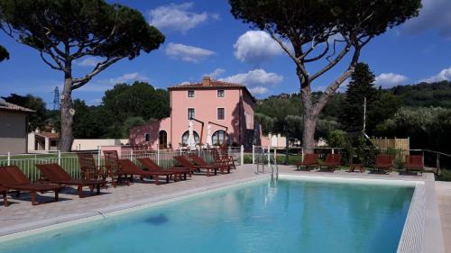 basen z krzesłami i budynek w tle w obiekcie Le Bozze -Villa Jenny con WI-FI, posto auto, piscina a sfioro a Castagneto Carducci w mieście Castagneto Carducci