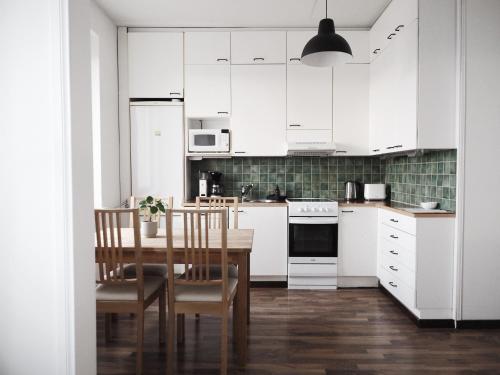 a kitchen with white cabinets and a table and chairs at 2ndhomes Tampere "Hatanpää" Apartment - Newly Renovated Downtown Apt in a Historic Building in Tampere