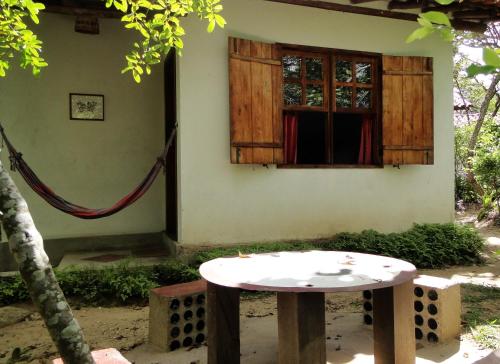 a table in front of a building with a window at Pousada Do Pequi in São Gonçalo do Rio das Pedras