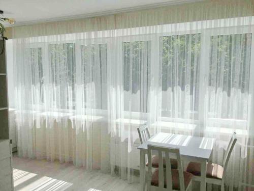 a dining room with white curtains and a table at Historical Centre Apartments in Lviv